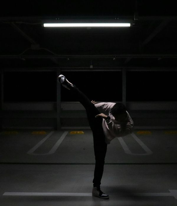 Man in a controlled strength training pose in a dark room.